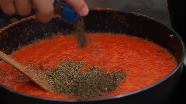 프라이팬의 파프리카 소스에 넣는 오레가노와 바질 가루