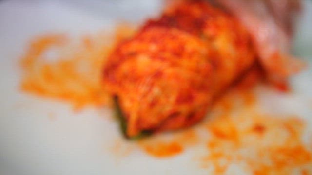 Kimchi being prepared by cutting with knife on a plate