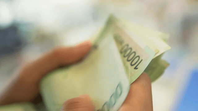 손에 든 한국 지폐를 세는 모습