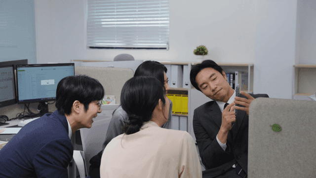 사무실에서 동료들에게 사진을 보여주는 사람
