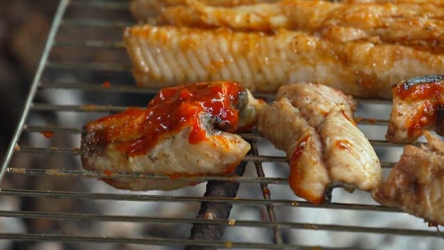 Applying sauce to eel grilled over charcoal