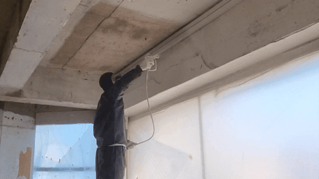Worker precisely painting the ceiling at a construction site