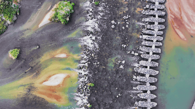 Aerial view overlooking a stone bridge across a clear river