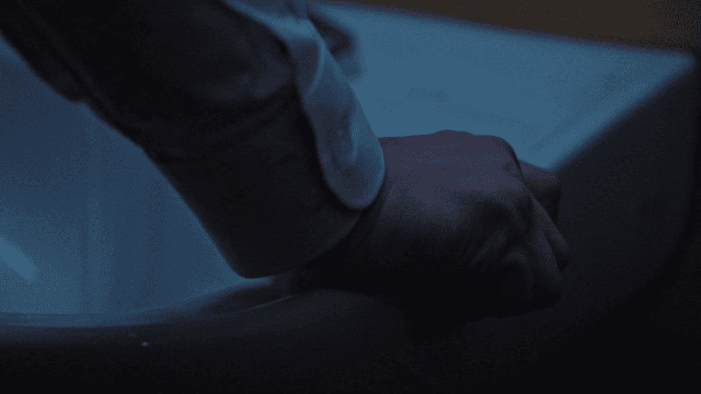 Angry hand gripping sink in dark bathroom