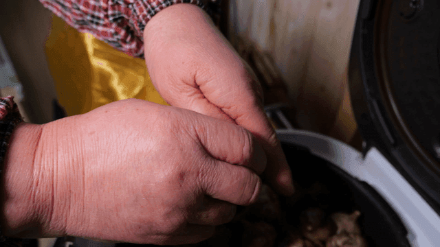 Hands peeling black garlic in a kitchen