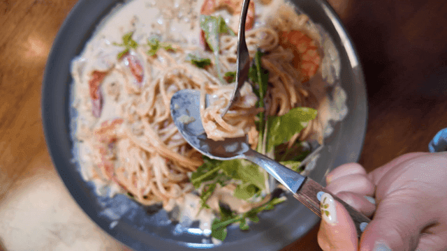 Cream pasta swirled onto spoon with fork