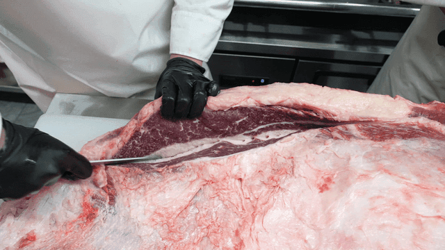 Butcher cutting large beef in meat shop