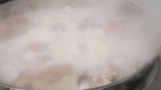 Boiling pot containing steaming pieces of meat
