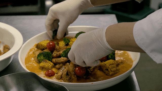 Chef garnishing a dish with vegetables