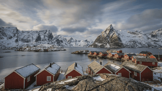 Snow-covered mountains and red cabins by the sea