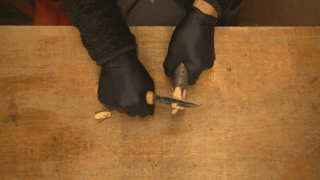 테이블 위에서 나무를 조각하는 손