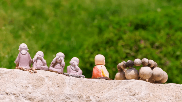 녹색 배경의 돌 위 작은 승려 조각상