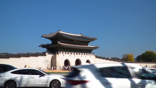 Busy street in front of Gyeongbokgung Palace, crowded with tourists under a clear blue sky