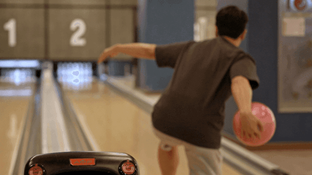 실내 볼링장에서 볼링을 치는 사람