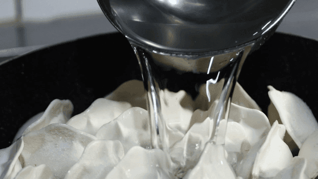 Water poured into frying pan containing dumplings