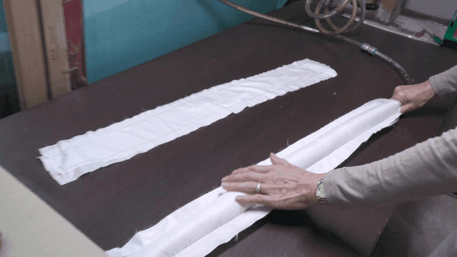 작업대 위 천에 뜨거운 바람을 넣는 사람