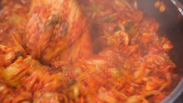 프라이팬에서 나무 주걱으로 매운 양배추 볶음을 만드는 모습
