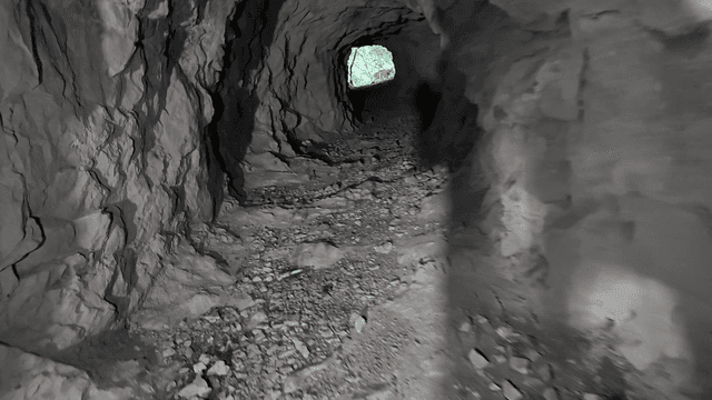 Rocky tunnel leading to a greenery exit