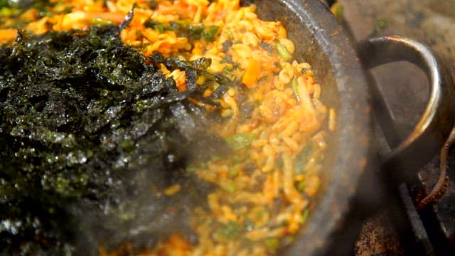 불판에서 신선한 채소와 비빔밥을 비비는 장면