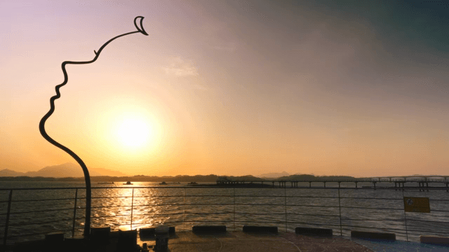 조각상과 함께 바다 위의 일몰 풍경