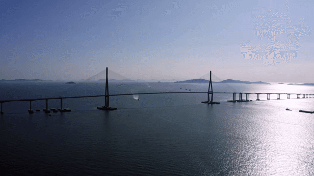 햇빛이 비추는 고요한 바다 위의 긴 다리와 배들
