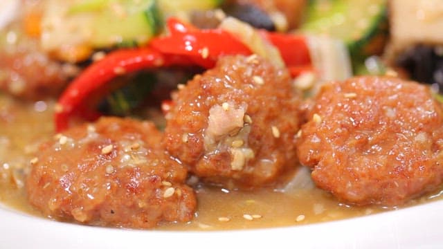 Appetizing stir-fried meatballs and vegetables sprinkled with sesame seeds