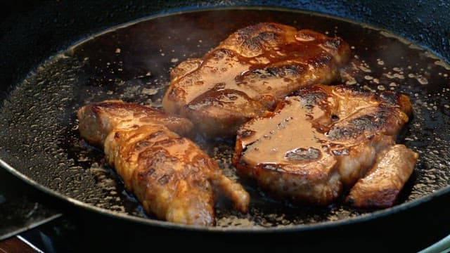 Grilling of juicy marinated pork on a hot frying pan