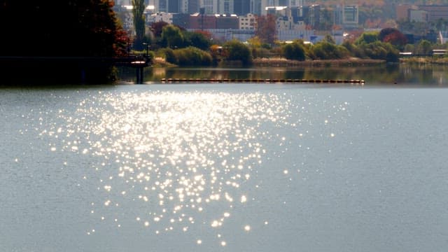 Baegunhosu Lake sparkling in the sunlight, surrounded by buildings and nature