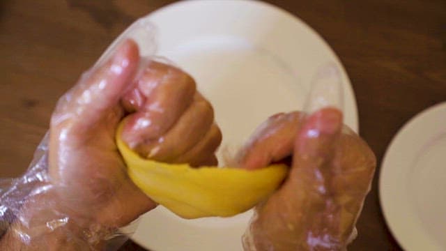 Hands Making Yellow Dough with Plastic Gloves 