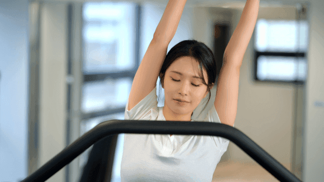 Woman stretching on a treadmill at gym