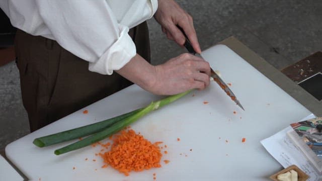 Slicing a Green Onion on a Cutting Board in the Kitchen