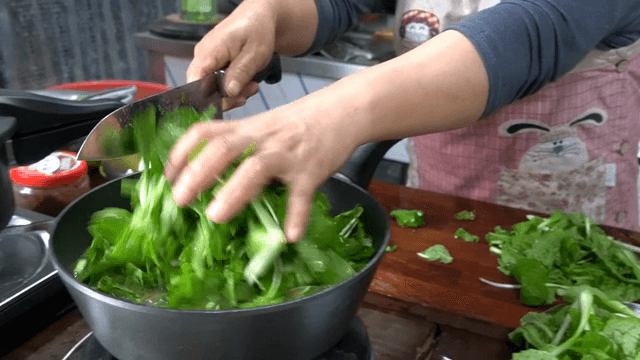 냄비에 채소를 썰어 넣는 장면