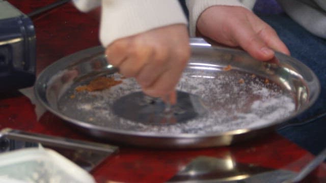 Pouring melted sugar onto a metal tray to make dalgona