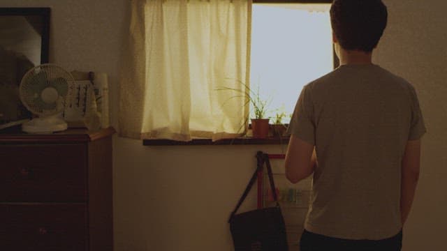 집에서 햇볕이 잘 드는 창문을 바라보며 담배를 피는 남자