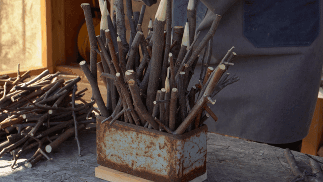 녹슨 용기에 나뭇가지를 정리해 꽂는 목공예가