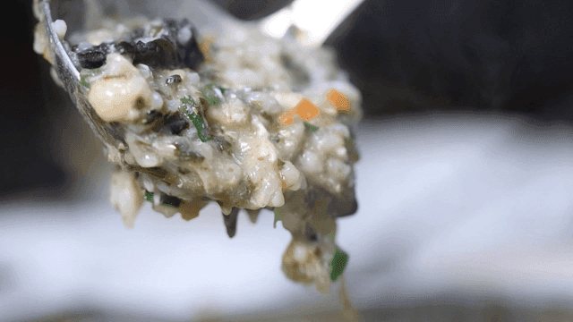 Ladleful of steaming vegetable porridge