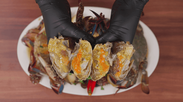 간장 게장 한 접시와 반 잘린 간장 게장들을 들고 있는 손