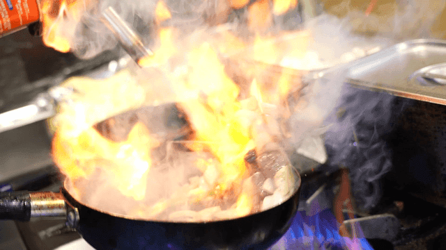 Frying pan on stove with rising flames