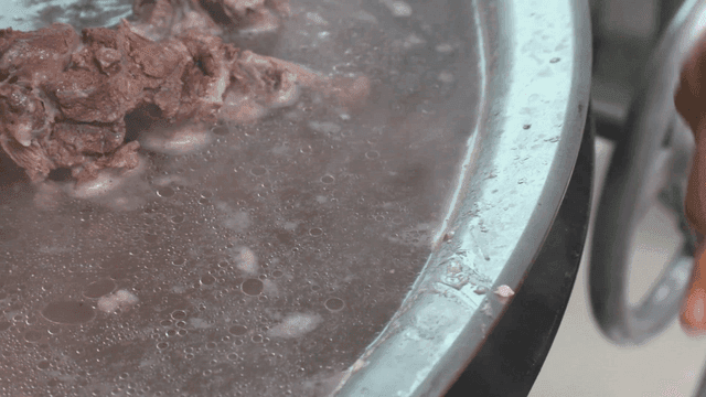 큰 냄비에서 불순물을 걸러내는 사람