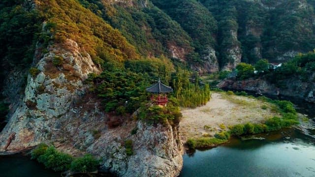 울창한 녹지로 둘러싸인 바위 절벽 위의 고요한 정자