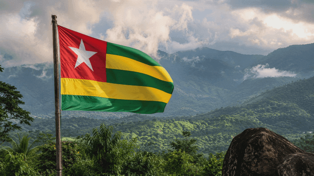Flag of Republic of Togo fluttering in front of blue mountains