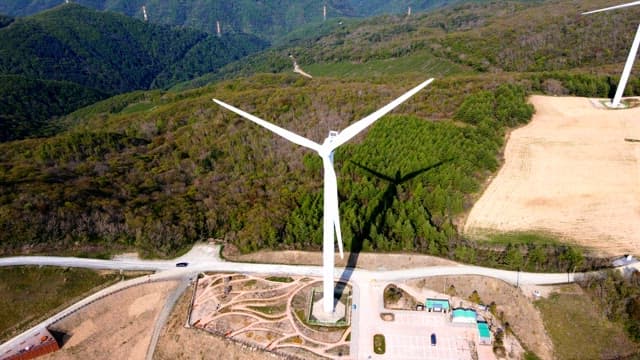 Wind turbines on top of a tree-filled mountain