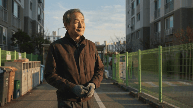 Elderly security guard standing at apartment recycling area