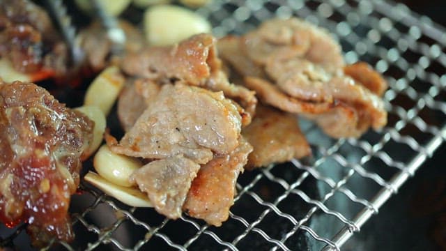 Grilling marinated pork ribs on a grill over burning charcoal