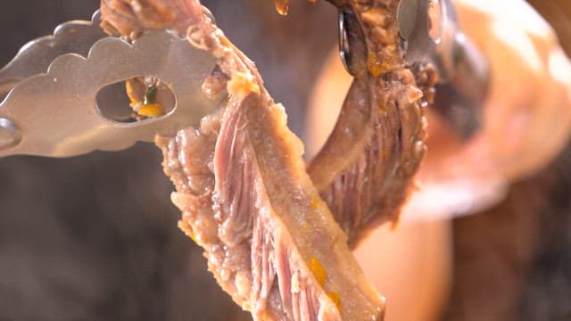 Ribs being torn apart with tongs while they are still steaming