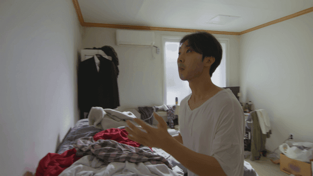 어수선한 방에서 벌레를 잡고 있는 남자