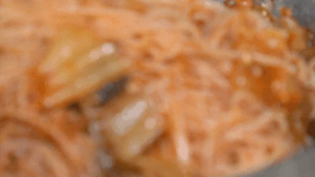 Mixing spicy bibim noodles with kimchi and sesame using chopsticks