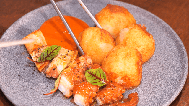 Chopsticks picking up crispy potatoes and grilled octopus