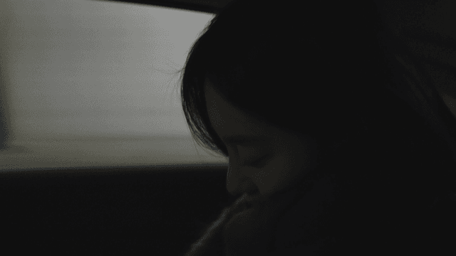 Profile of a woman looking out the window of a taxi into a dark tunnel