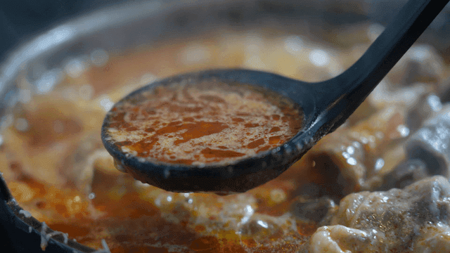 Ladle serving boiling cheese mala hotpot broth